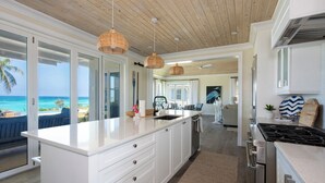A modern kitchen with white cabinetry, a large island, and a view of the ocean.