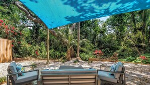 An outdoor seating area with two benches and a table, surrounded by lush greenery and a wooden fence. - Oasis 3beds- 5minutes to beach -air hockey, foosball, pacman - beautiful murals! (Largo)
