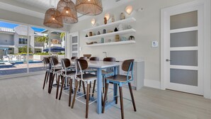 A modern dining area with a pool view, white walls, and blue chairs.