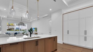 A modern kitchen with a large island, wooden cabinets, and pendant lighting.