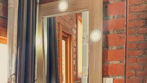 Un baño con tocador de madera, un espejo con iluminación y una pared de ladrillo.