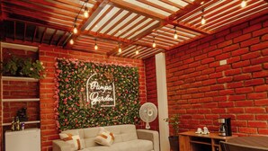 Una habitación acogedora con pared de ladrillo, techo de madera, un sofá, un ventilador y un letrero que dice "Pampa Garden".