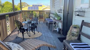 A wooden deck with outdoor furniture, including a wicker chair and a table, and a small garden area with potted plants.