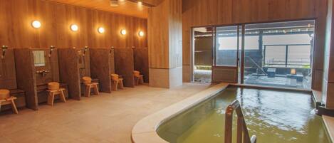 A modern spa area with wooden walls, a pool, and multiple shower stalls.