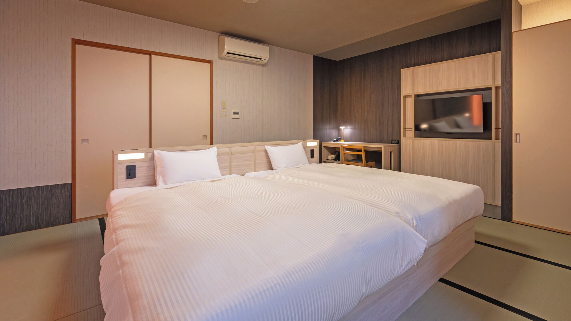 Une chambre d’hôtel avec un grand lit, un bureau avec une chaise, une télévision et un appareil de climatisation.