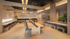 Una cafetería moderna y amplia con mesas comunitarias largas, asientos individuales y un diseño minimalista.