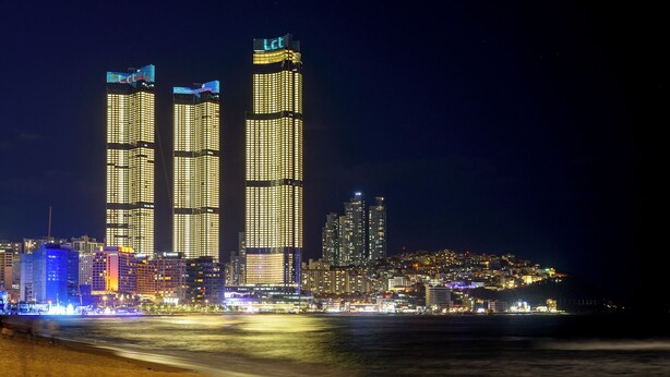 A nighttime cityscape with illuminated skyscrapers and a beach in the foreground. - LCT residence THE VINE Haeundae (Busan)