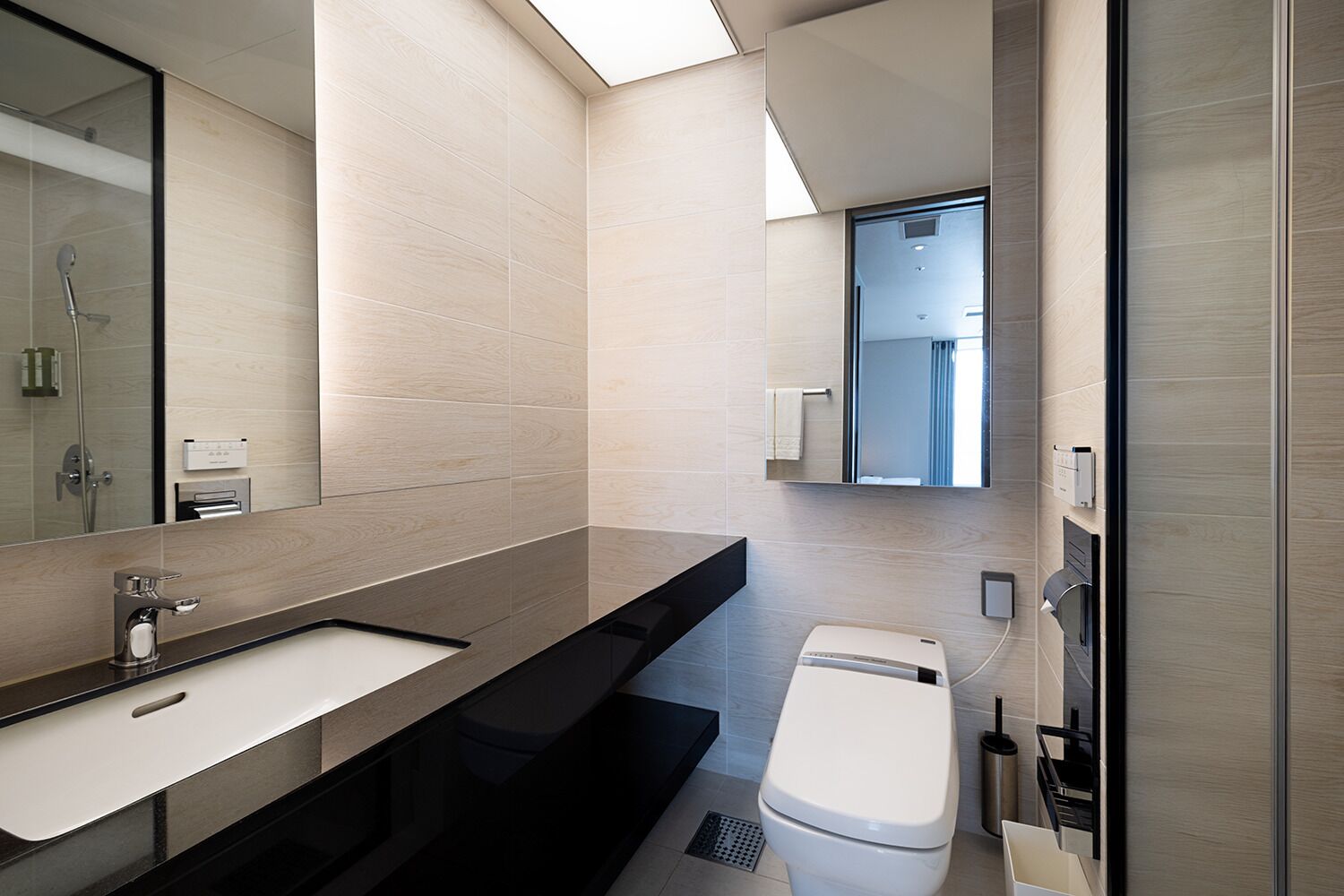 Een moderne badkamer met een grote spiegel, een wastafel, een toilet en een douche.