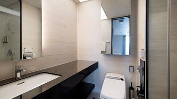 Een moderne badkamer met een grote spiegel, een wastafel, een toilet en een douche.