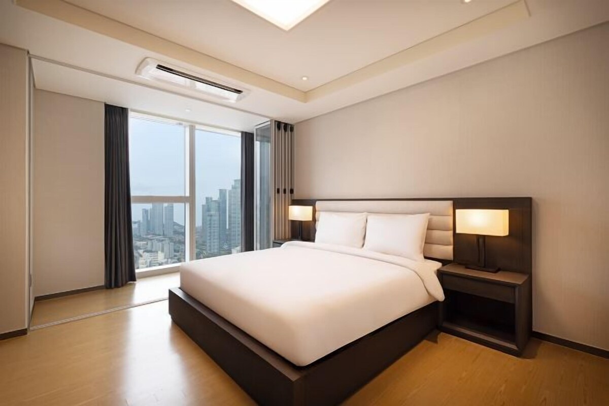Ein modernes Hotelzimmer mit einem großen Bett, einem Nachttisch und Blick auf die Stadt.