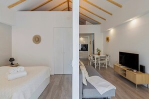 Une chambre moderne et bien éclairée, comprenant un lit, un canapé, un coin repas et un téléviseur.
