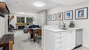 Una cocina moderna con armarios blancos, una isla integrada y un comedor con chimenea de piedra.