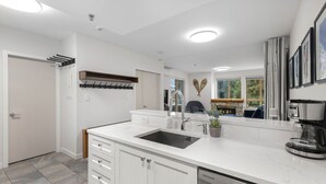 Una cocina moderna con armarios blancos, un lavamanos integrado y una cafetera.