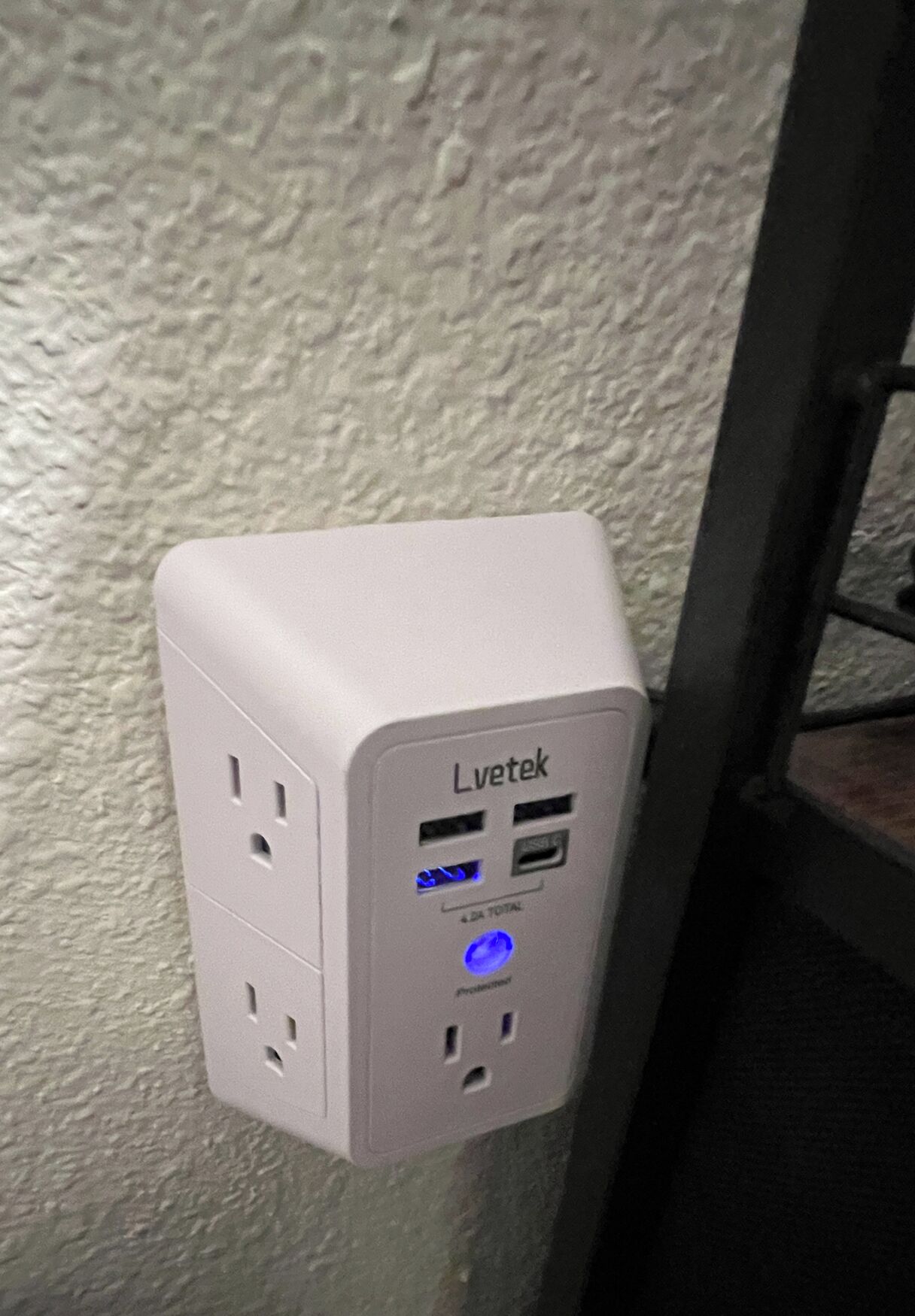 A Lvetek power strip with multiple outlets and USB ports, mounted on a textured wall.