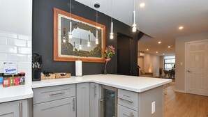 A modern kitchen with grey cabinets, a white countertop, and a decorative mirror. - Elegant SoHo 5BR Duplex – Upscale, Central & Spacious (New York)