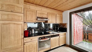 A kitchen with wooden cabinets, a black countertop, and a stainless steel oven. - Mountain Bliss, view and Sauna - Swiss Alps (Anzère)