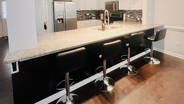 Een moderne keuken met een centraal eiland, barstoelen en roestvrijstalen apparatuur.