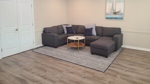 A modern living room with a sectional sofa, a small round coffee table, and a patterned rug. - Downtown Marblehead 2brm/1.5bath w/ deck (Marblehead)