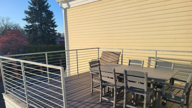 A wooden deck with a metal railing, a table, and chairs. - Downtown Marblehead 2brm/1.5bath w/ deck (Marblehead)