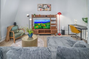 A modern living room with a flat-screen TV, a sofa, a desk, and a red floor lamp.