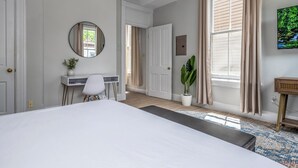 A bedroom with a large bed, a desk, a chair, a potted plant, and a television on the wall. - Prime Mt Adams+Lux Beds+Sleeps 6ppl+Deck Views+Smart TVs+Spacious Living Rooms (Cincinnati)