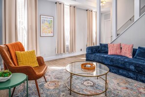 A living room with a leather armchair, a blue sofa, and a glass coffee table.