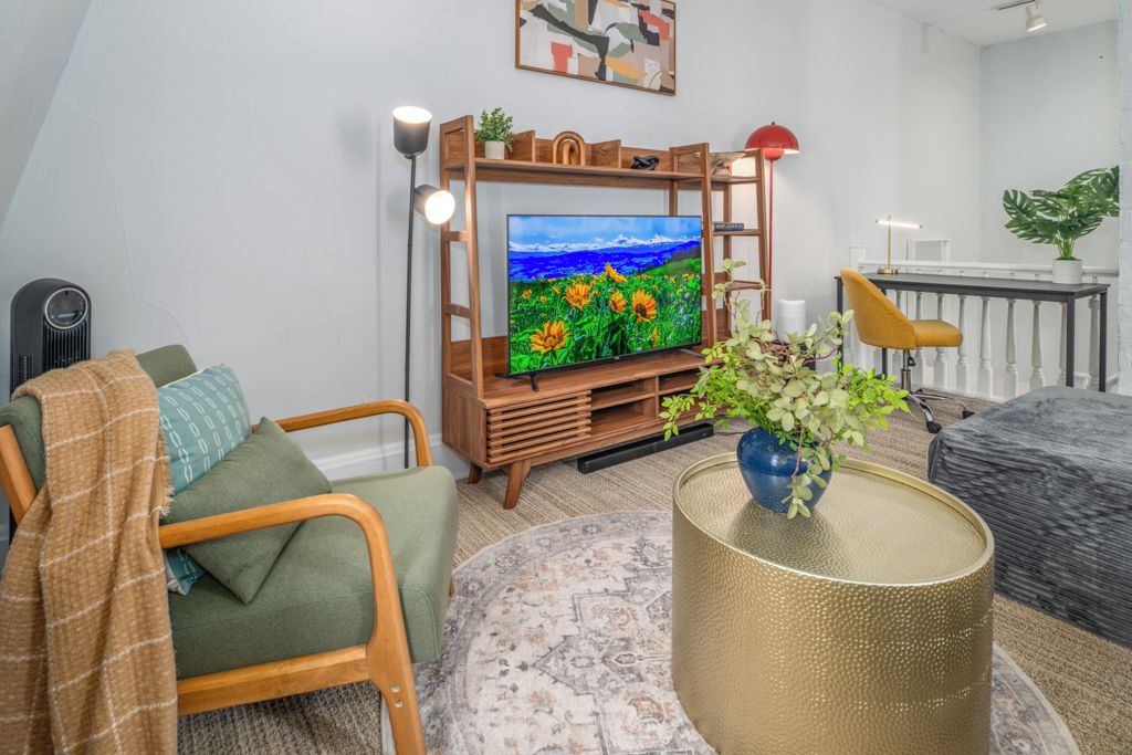Een woonkamer met een televisie, een bank, een salontafel en een plant.