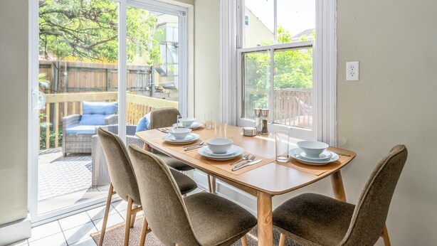 A dining area with a table set for four, large windows, and a view of the backyard. - Prime Mt Adams+Lux Beds+Sleeps 6ppl+Deck Views+Smart TVs+Spacious Living Rooms (Cincinnati)