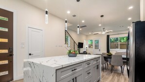 A modern kitchen with a marble island, grey cabinets, and a dining area with a table and chairs. - 3-bedroom house in welcoming Houston with WiFi, AC, EV Charging (Houston)