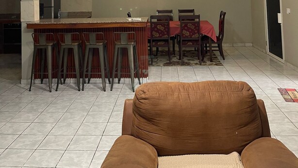 A spacious living area with a high ceiling, a central island with stools, a dining table with chairs, and a brown sofa. - Charming 2-bedroom house with AC, WiFi in enjoyable and expacious house (Cantón Quitasol)