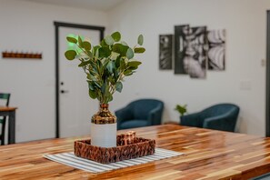 A wooden dining table with a vase of green leaves and a woven basket.