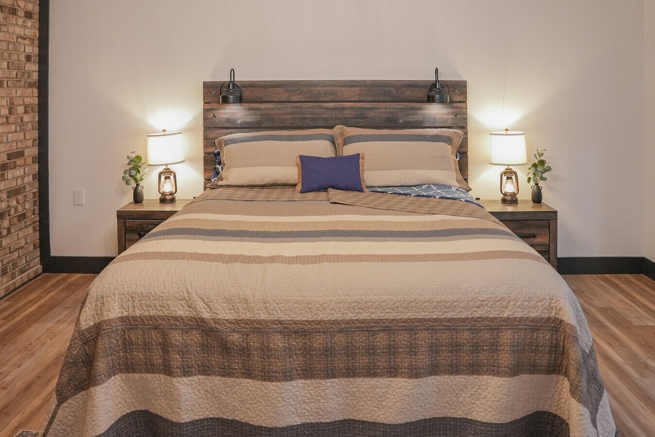 A neatly made bed with a striped bedspread, two bedside lamps, and a wooden headboard.