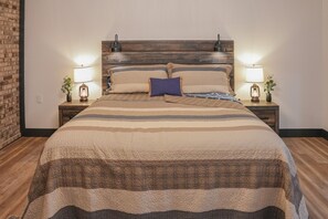 A neatly made bed with a striped bedspread, two bedside lamps, and a wooden headboard.