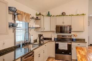 A modern kitchen with white cabinets, stainless steel appliances, and a granite countertop.