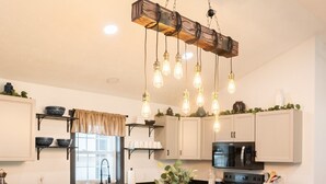 Una cocina moderna con una isla de madera, taburetes de bar e iluminación colgante.
