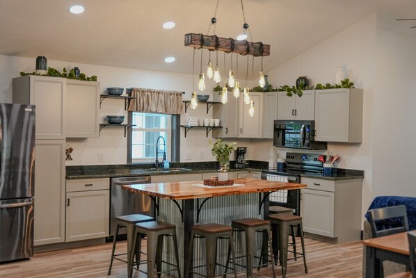 A modern kitchen with a central island, bar stools, and pendant lighting.
