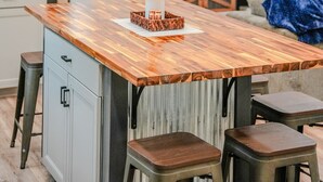 Une cuisine moderne avec un îlot central en bois, des tabourets de bar, un téléviseur et un luminaire au plafond au design original.