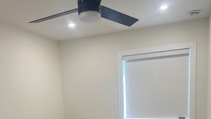 A bedroom with a bed, a nightstand, a ceiling fan, and a window with blinds. - Panorama ridge suite (Surrey)