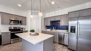 A modern kitchen with stainless steel appliances, a central island, and pendant lighting.