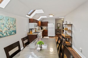 Una cocina moderna con comedor, que cuenta con tragaluces, armarios de madera y encimera de granito.