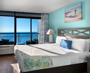 A bedroom with a large bed, a view of the sea, and a balcony with a chair.