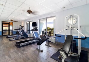 Un gimnasio con cintas de correr, elípticas y un banco de pesas.