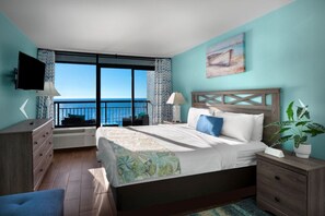 Un dormitorio con una cama grande, televisión, planta y vista al mar.