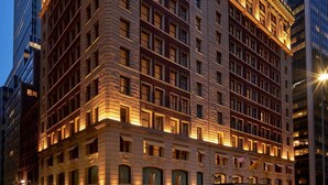 Un hotel de varios pisos con estilo arquitectónico clásico, que destaca por su entrada en esquina y grandes ventanales.