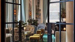 Una habitación con alfombra verde, un ventanal con cortinas y un candelabro.