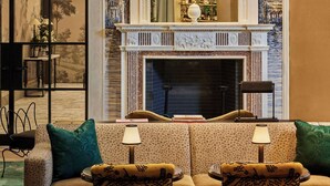 A cozy lounge area with a fireplace, two patterned armchairs, and a bar area with bottles.