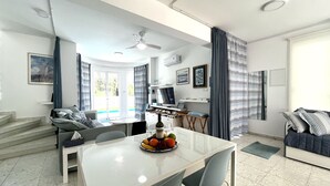 A modern living room with a dining area, a staircase, and a view of the outdoors. - STAY ALKYONI Villa (Protaras)