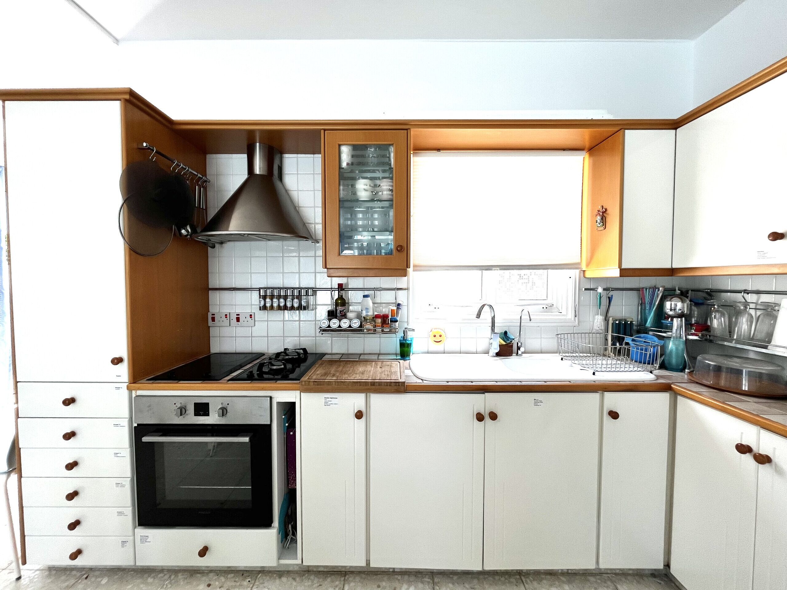 Una cocina con armarios blancos, estufa, horno y lavaplatos.