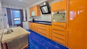 A compact kitchen with orange cabinets, a blue tiled backsplash, and a built-in oven. - Katorse, 2 bedrooms, 2 bathrooms and elevator (Bermeo)