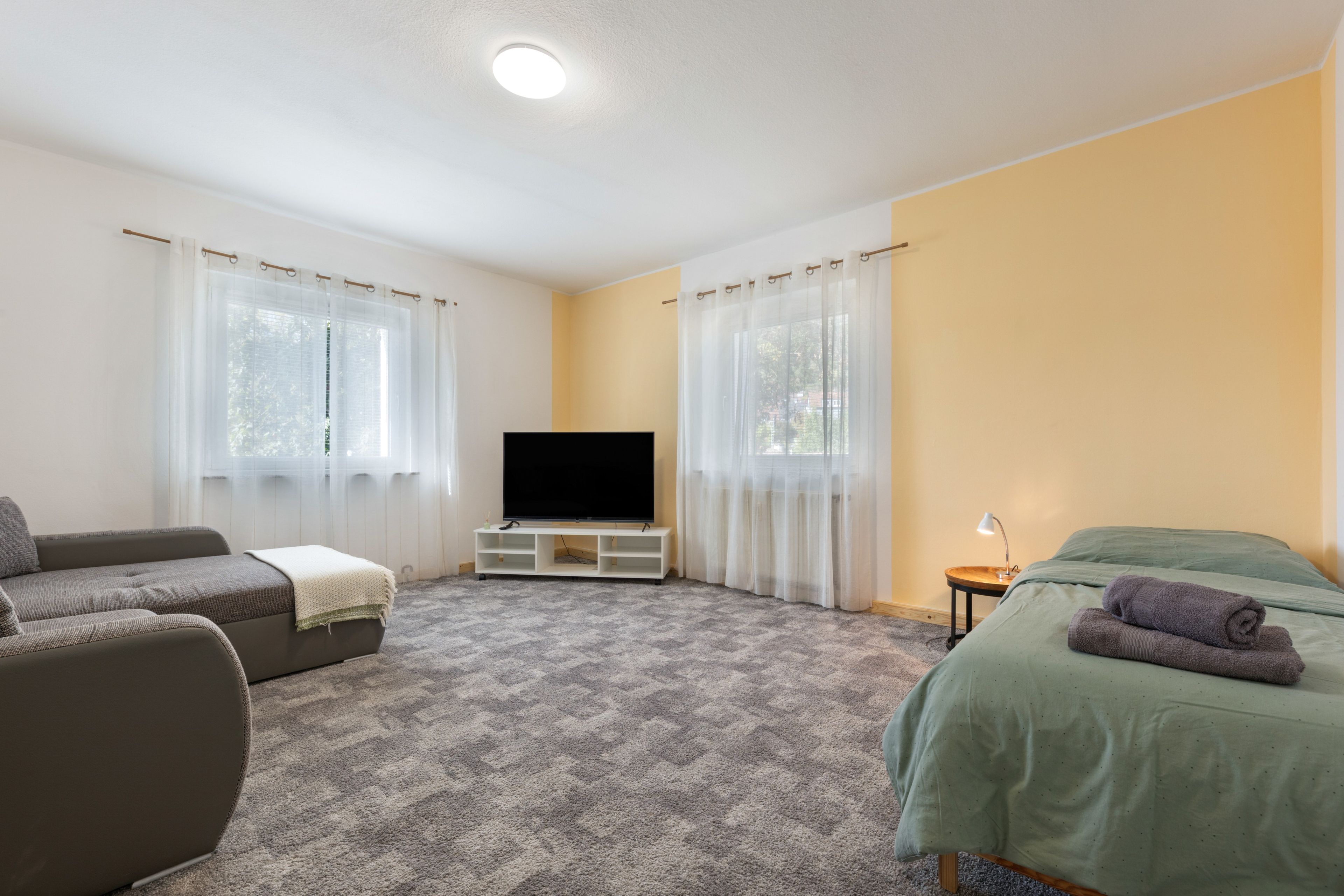 A hotel room with a sofa, a bed, a TV, and a small table.
